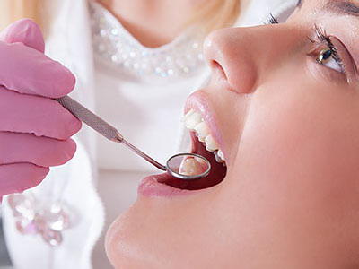 A dental professional performing a dental procedure on a patient s teeth with specialized equipment.