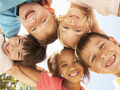 A group of children with different expressions are huddled together, smiling at the camera.