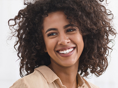 A woman with curly hair smiling broadly at the camera.